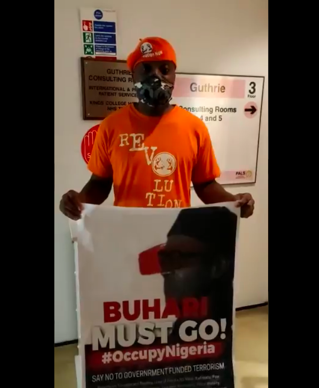 Watch As Nigerian In UK Begins Lone Protest After Gaining Entrance Into Buhari’s Hospital